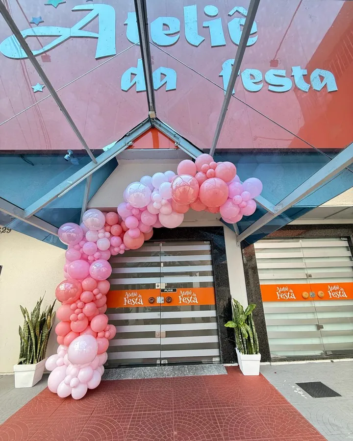 Entrada do Ateliê da Festa com arco de balões cor-de-rosa e tapete vermelho