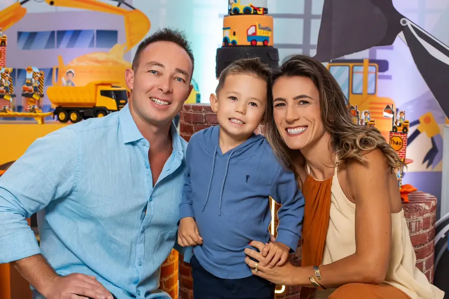 Pais e filho sorrindo no cenário com tema construção