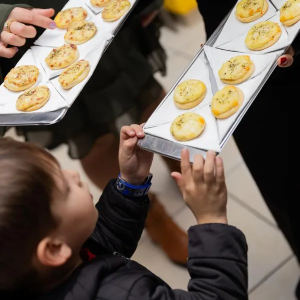 Garçom servindo bandejas de salgados a um menino na festa