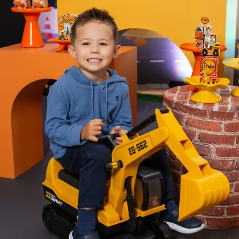 Menino brincando em uma escavadeira de brinquedo na festa com tema construção