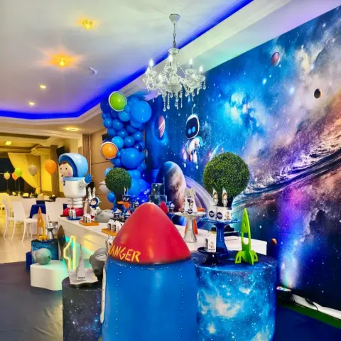 Foguete decorativo e painel de galáxia na festa com tema espacial
