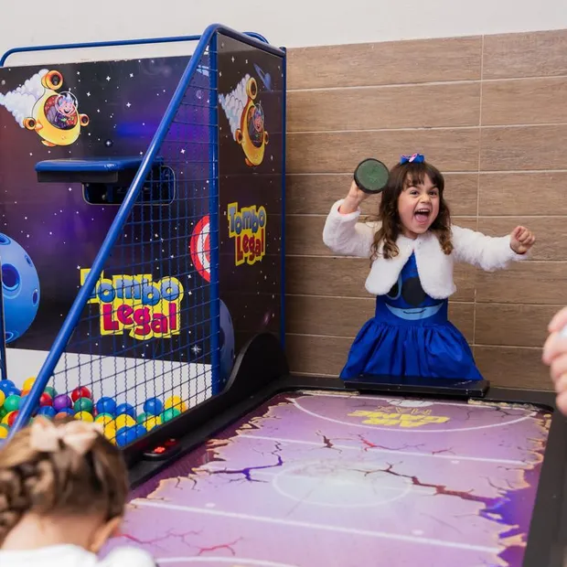 Menina comemorando na mesa de air hockey do parque