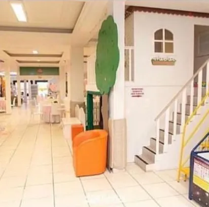 Casinha de boneca branca com escada e árvore decorativa no salão